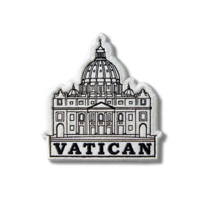 May include: A white embroidered patch featuring a black line art illustration of St. Peter's Basilica in the Vatican. The design includes the iconic dome and architectural details, with the word VATICAN printed in bold black capital letters below.