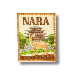 Puede incluir: Un parche bordado rectangular con la palabra NARA en hilo marrón en la parte superior. Debajo del texto hay una pagoda marrón rodeada de árboles verdes y un ciervo claro con manchas blancas sobre un suelo marrón.