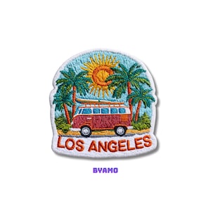 May include: Embroidered patch featuring a red and white van with a surfboard on top, palm trees, and a bright sun. The text "LOS ANGELES" is in orange, with the word "BYAMO" below. The patch has a white border.