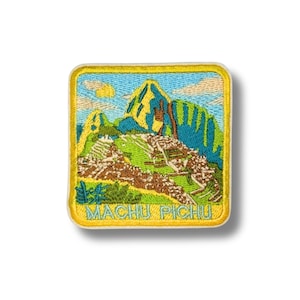 May include: Embroidered patch featuring a colorful depiction of Machu Picchu, with a yellow border and the text "MACHU PICCHU" in blue. The patch showcases the mountain landscape with green, yellow, and brown hues, set against a blue sky with clouds.
