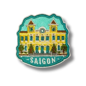 May include: Embroidered patch featuring a yellow building with a teal background and border. The building has multiple windows, doors, and two towers. The word "SAIGON" is embroidered in teal at the bottom.