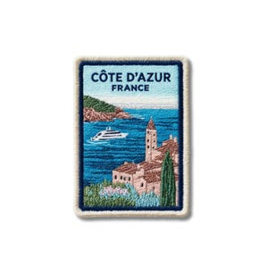 Op de afbeelding: Een rechthoekige geborduurde patch met een kustscène van de Côte d'Azur, Frankrijk. Het ontwerp bevat een blauwe zee, een wit jacht, een stenen klokkentoren, gebouwen met terracotta daken, groene cipressen en de tekst Côte d'Azur France.