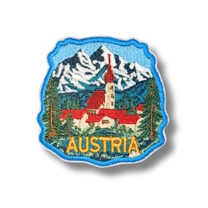 Peut inclure: Un écusson brodé représentant un paysage de montagne avec des sommets enneigés, une église au toit rouge avec un clocher et des sapins verts. Le mot AUSTRIA est brodé en lettres capitales jaunes au bas du motif à bordure bleue.