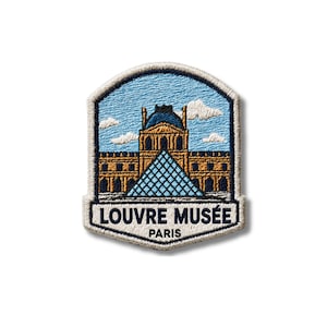 May include: An embroidered patch featuring the Louvre Museum in Paris, showcasing the iconic glass pyramid and building architecture against a light blue sky with white clouds. The text LOUVRE MUSÉE PARIS is stitched in dark blue at the bottom.