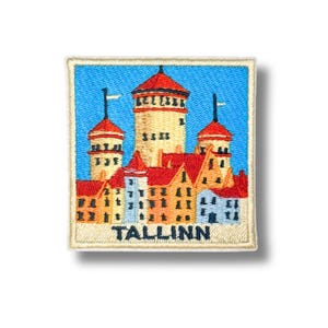 May include: A square embroidered patch featuring a colorful depiction of the Tallinn skyline against a bright blue sky. The design includes tan towers with red roofs and various buildings in shades of yellow, orange, and blue. The word TALLINN is stitched in dark blue at the bottom.