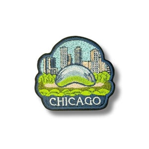 May include: An embroidered patch featuring a stylised Chicago skyline with the iconic silver bean-shaped sculpture in the foreground, surrounded by green parkland. The word CHICAGO is stitched in white capital letters on a dark blue base.