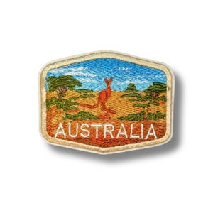 May include: Embroidered patch depicting a kangaroo in a desert scene under a blue sky. The patch has a cream border and the word "AUSTRALIA" in orange lettering.