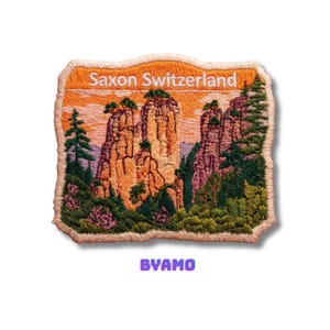 Puede incluir: Parche bordado con una vista de la Suiza Sajona, con texto en la parte superior. El diseño muestra imponentes formaciones rocosas, árboles verdes y un cielo naranja. La palabra "BYAMO" está en la parte inferior.