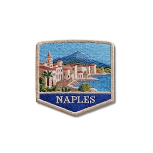 Könnte beinhalten: Ein schildförmiger Stickaufnäher mit einer Küstenszene von Neapel, weißen Gebäuden, einem hohen Turm und einem Berg im Hintergrund. Das blaue Meer ist zu sehen und das Wort NAPLES ist in weißen Buchstaben auf einem dunkelblauen Banner gestickt.
