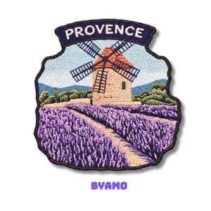 Può includere: Toppa ricamata raffigurante un mulino a vento in un campo di lavanda sotto un cielo blu. La parola "PROVENCE" è arcuata nella parte superiore. La parola "BYAMO" è in basso. La toppa ha un bordo nero.