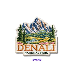 Può includere: Toppa ricamata raffigurante una catena montuosa con cime blu e alberi verdi. La toppa recita "DENALI NATIONAL PARK" in lettere dorate. Il testo "BYAMO" è in basso in viola.