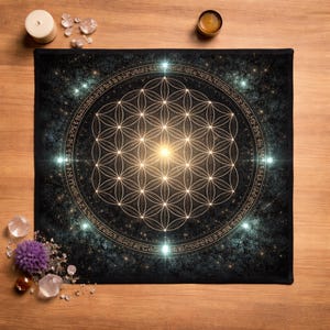May include: Black rectangular mat featuring a gold geometric flower of life design. The design is surrounded by a gold circular border with text. The background is a dark, starry pattern. Crystals and candles are arranged around the mat.