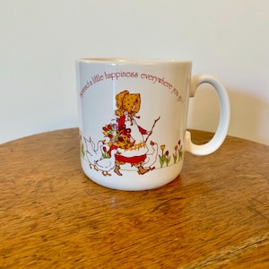 Vintage Holly Hobbie “Spread a little happiness everywhere you go” Mug. Made in Japan  Measures 3” diameter, 4.5” to handle & stands 4” tall