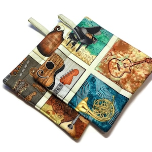 May include: Two colorful pot holders with a musical theme. The pot holders feature a variety of musical instruments, including a piano, guitar, and a french horn. The pot holders are made of fabric and have a quilted design.