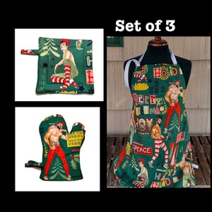 May include: Set of three green Christmas kitchen accessories with a festive holiday print featuring men in Santa suits. The set includes an apron, a pot holder, and an oven mitt. The print features the words "Holly Jolly", "Peace", "Joy", and "Merry Christmas".