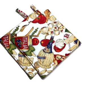 May include: Two square pot holders with a white background and an Italian food-themed pattern. The pattern includes images of tomatoes, garlic, pasta, olive oil bottles, and the word "Italia". Each pot holder has a loop for hanging.