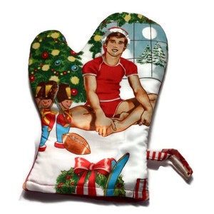 May include: A red and white Christmas oven mitt with a festive design featuring a man in a Santa hat, a Christmas tree, and toy soldiers.