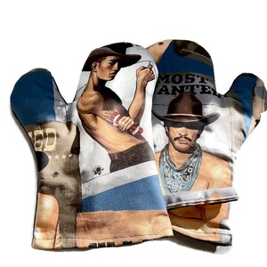 May include: A pair of oven mitts with a vintage western theme. The mitts feature a collage of images including cowboys, wanted posters, and a blue and white striped pattern. The text "MOST WANTED" is visible on one mitt.