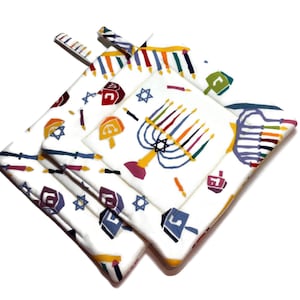 Puede incluir: Manoplas de cocina de algodón blanco con diseños coloridos con temática de Janucá. Los diseños incluyen menorás, dreidels, velas y estrellas de David. Las manoplas tienen una textura acolchada y un lazo para colgar.