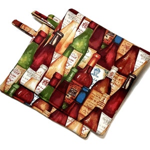 May include: A pair of red and beige pot holders with a colorful pattern of wine bottles. The pot holders have a loop handle on each side.