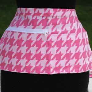 May include: Pink and white houndstooth apron with a white zippered pocket.