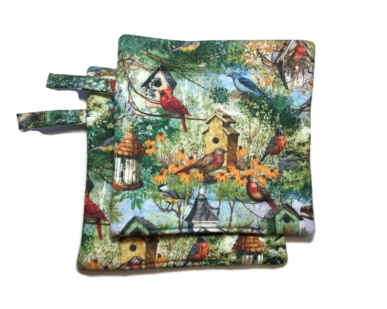 May include: Two green, brown, and blue pot holders with a birdhouse and bird pattern. The pot holders have a loop handle.