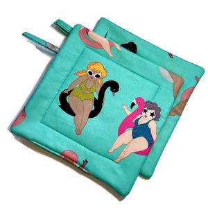 May include: Two turquoise blue pot holders with a white stitched border. The pot holders feature a repeating pattern of women in swimsuits on a turquoise background. One woman is on a black swan, another is on a pink flamingo, and the third is on a pink inner tube.