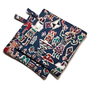 May include: A pair of blue quilted pot holders with a colorful Native American design. The pot holders have a loop handle on each side.