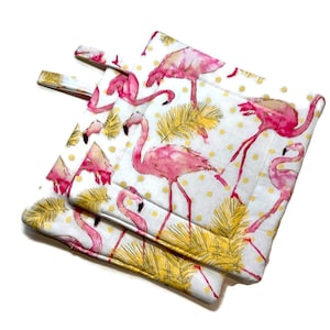 May include: Two pink flamingo pot holders with yellow palm leaves and white polka dots on a white background.