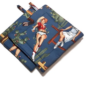 May include: Two blue quilted pot holders with a pattern of pin-up style women in cowboy hats and cacti on a blue background.