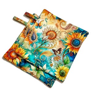 May include: Two square pot holders with a vibrant sunflower and butterfly design. The pot holders feature a watercolor style with yellow, orange, teal, and blue hues. Each pot holder has a loop for hanging.
