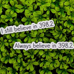 May include: Two white stickers with black text on a green leafy background. The top sticker reads "I still believe in 398.2". The bottom sticker reads "Always believe in 398.2".