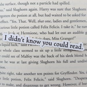 May include: A white sticker with the text "I didn't know you could read." The sticker is placed on a page of a book with text about a potion called Felix Felicis.