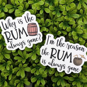 Op de afbeelding: Twee witte stickers met zwarte tekst en illustraties. De eerste sticker zegt "Waarom is de RUM altijd weg?" met een cartoon rumvat. De tweede sticker zegt "Ik ben de reden dat de RUM altijd weg is" met een cartoon kokosnoot met een rietje.