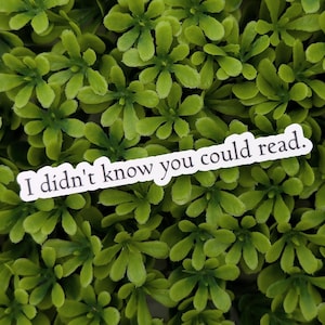 Puede incluir: Pegatina blanca con el texto "No sabía que podías leer." sobre un fondo de hojas verdes.