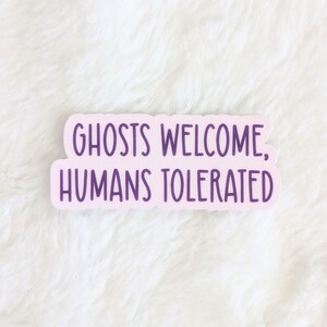 May include: A pink sticker with purple text that reads "Ghosts Welcome, Humans Tolerated".