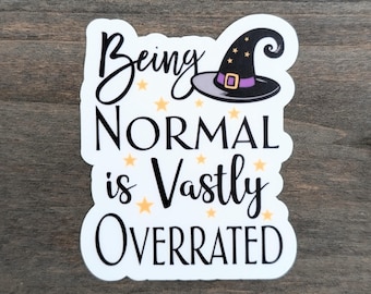 May include: A white sticker with the text "Being NORMAL is Vastly OVERRATED" in black script and block letters. A witch's hat with a purple band and gold stars is above the word "NORMAL".