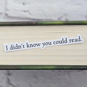 May include: A white sticker with the text "I didn't know you could read." is placed on the spine of a book.
