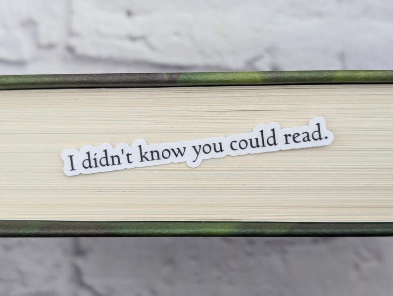 May include: A white sticker with the text "I didn't know you could read." is placed on the spine of a book.