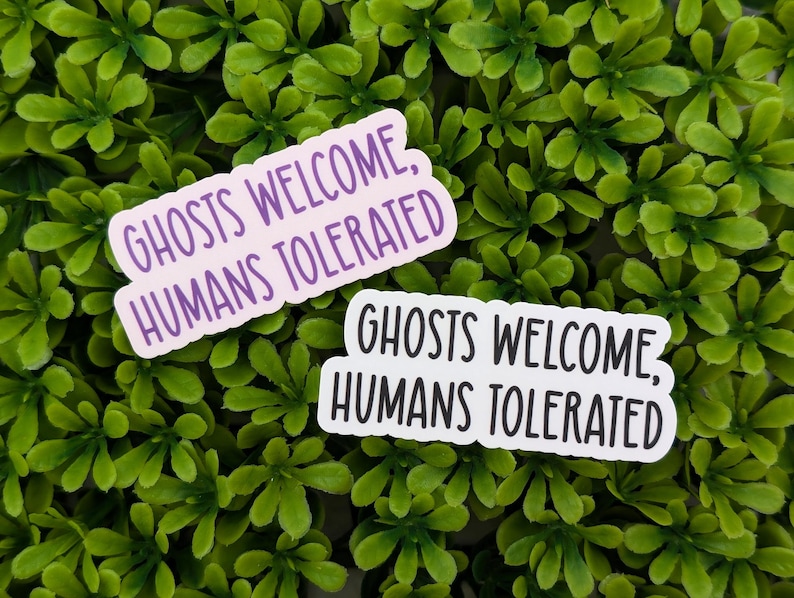 May include: Two white stickers with purple text on a green background. The text on the stickers reads "Ghosts Welcome, Humans Tolerated".