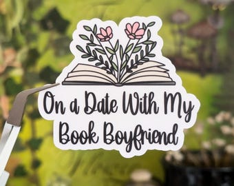 May include: A white sticker with a black outline features an open book with pink flowers growing from it. The text "On a Date With My Book Boyfriend" is written in black cursive.