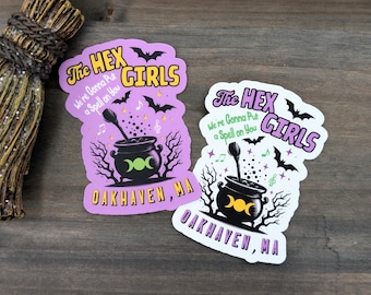 May include: Two colorful stickers with a witchy theme. The stickers feature the text "The Hex Girls" and "We're Gonna Put a Spell on You" with a cauldron, bats, and musical notes. The town name "Oakhaven, MA" is also included.