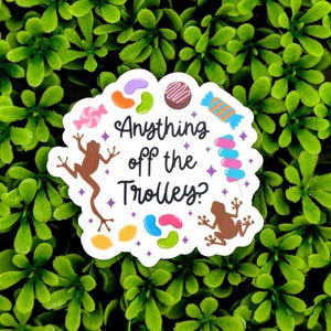 May include: White sticker with the text "Anything off the Trolley?" surrounded by colorful candy, frogs, and stars.