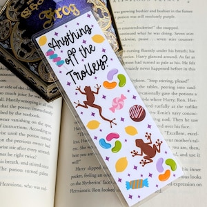 Könnte beinhalten: Ein weißes Lesezeichen mit einem lila, rosa und gelben Design. Das Lesezeichen zeigt einen Frosch, Süßigkeiten und den Text "Anything off the Trolley?"