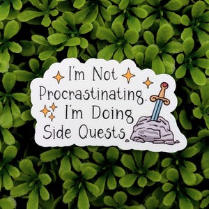 May include: A white sticker with the text "I'm Not Procrastinating. I'm Doing Side Quests." features a cartoon sword in a stone design. The sticker has a decorative border and star accents, set against a green leafy background.