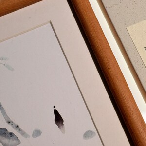 Op de afbeelding: Aquarel schilderij van een tak met bladeren, omlijst in een houten frame. Een doos met de tekst "Indian sandalwood Mindfree Space" staat naast het ingelijste kunstwerk. Het kunstwerk heeft een minimalistische stijl.