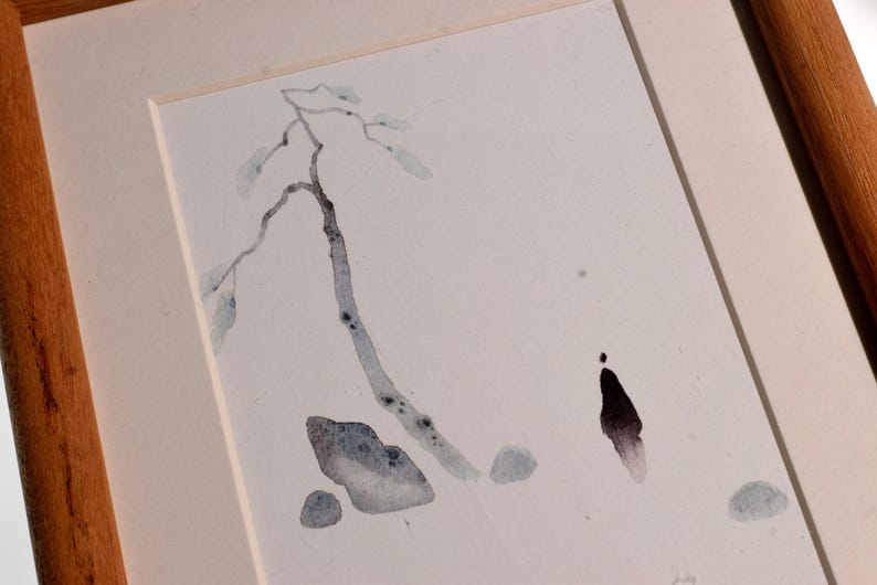 Op de afbeelding: Aquarel schilderij van een boomtak met bladeren en een figuur, in een houten lijst. Het kunstwerk toont gedempte blauw- en grijstinten op een witte achtergrond. De lijst is lichtbruin.