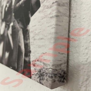 May include: Monochrome canvas print featuring a person in a coat. The canvas is stretched over a wooden frame, with the edges in view. The image is a close-up, highlighting the texture of the canvas and the artwork's details.