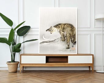 May include: A black and white illustration of a tiger roaring with a crescent moon in the background. The tiger is standing on a snowy mountaintop. The illustration is framed and hanging on a wall above a wooden shelf.