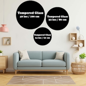 Op de afbeelding: Drie zwarte, cirkelvormige wandkunstwerken van gehard glas in verschillende maten: 40 inch (100 cm), 32 inch (80 cm) en 24 inch (60 cm). Elk stuk heeft witte tekst die de grootte aangeeft. De kunst wordt boven een blauwe bank getoond.